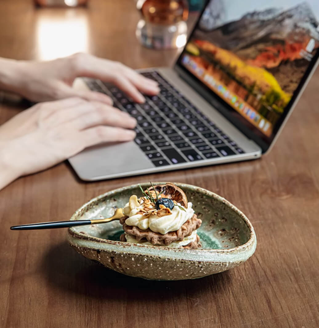 Artisan Green Dinnerware bowl with dessert, featuring speckled glaze and a dessert with berries and nuts.